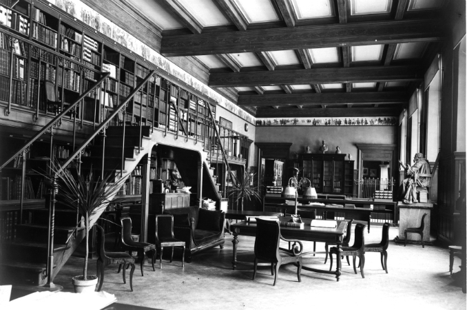 Vue d'ensemble d'une salle de la bibliothèque, avec escaliers permettant d'accéder au niveau supérieur des étagères